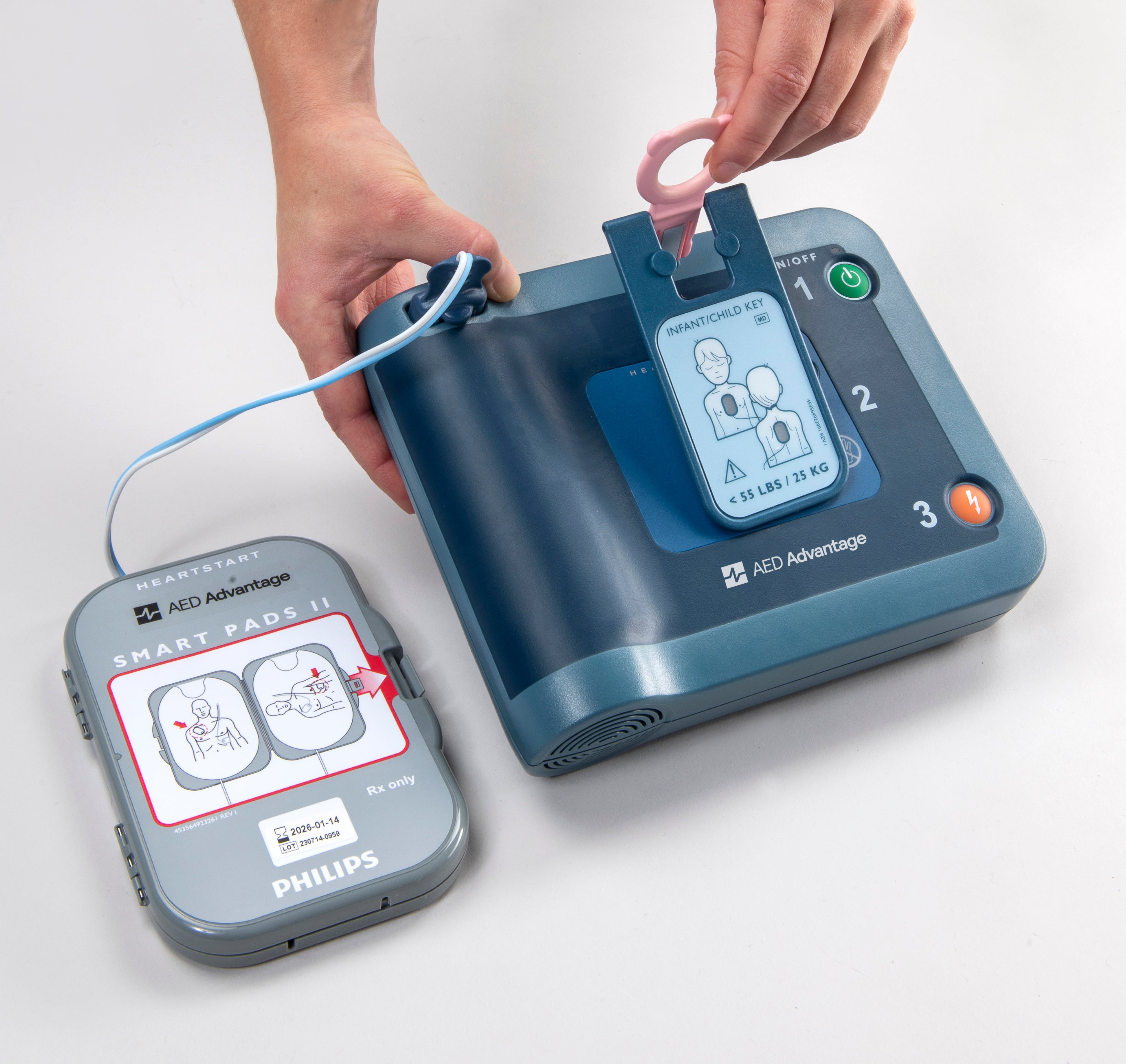 Someone is inserting a pediatric key into a blue Philips HeartStart FRx AED