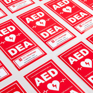 A collage of large red rectangular decals that adhere to the side of AED storage cabinets to increase their visibility