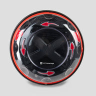 A black and yellow, spherical defibrillator cabinet with red arrows indicating which way to turn the lid to open it