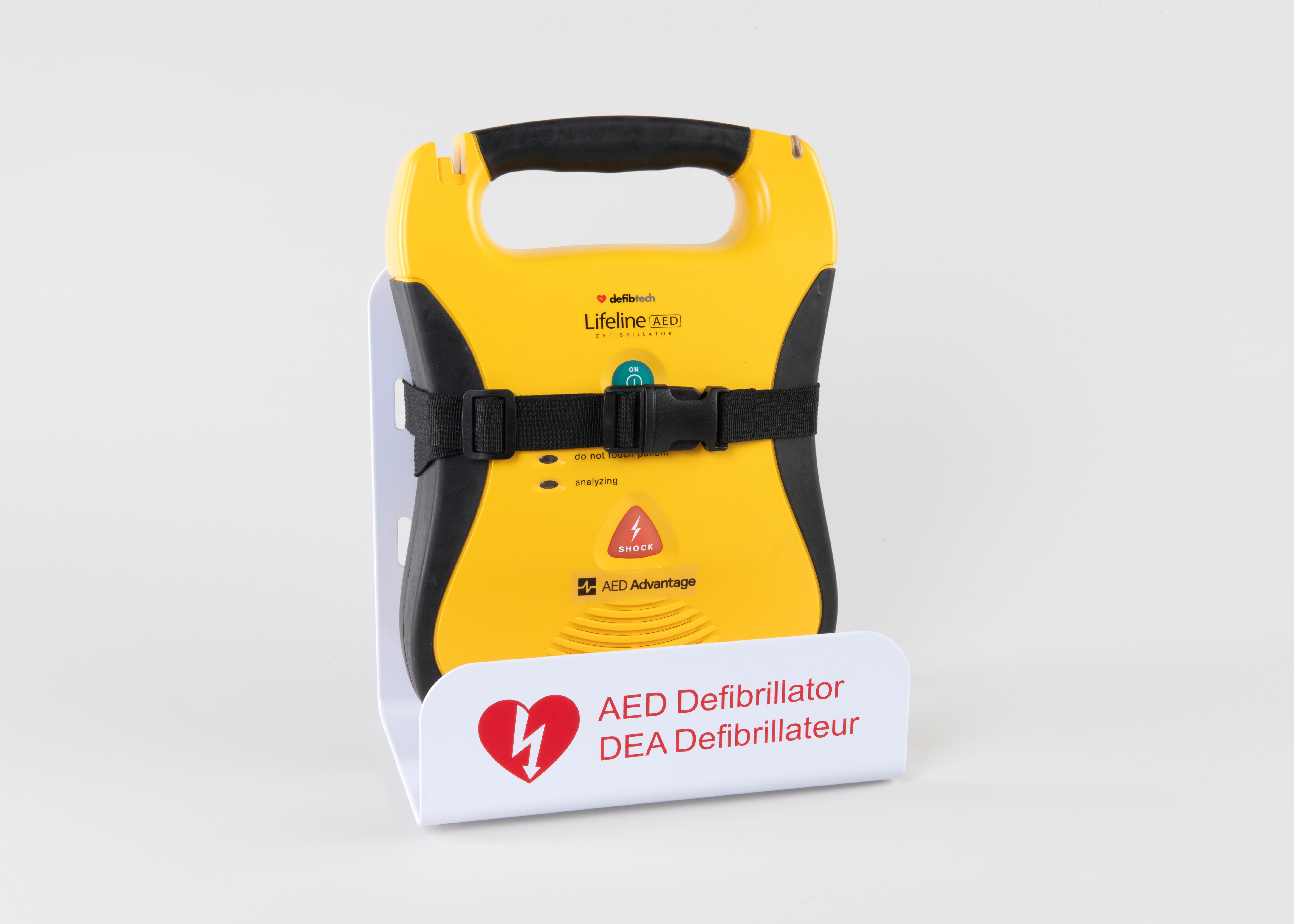 A black and yellow Defibtech Lifeline AED strapped into a white metal wall mount bracket