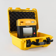 A black and yellow LIFEPAK 1000 AED machine inside a bright yellow hardshell carry case