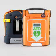 An orange Powerheart G5 AED standing next to its gray carry case