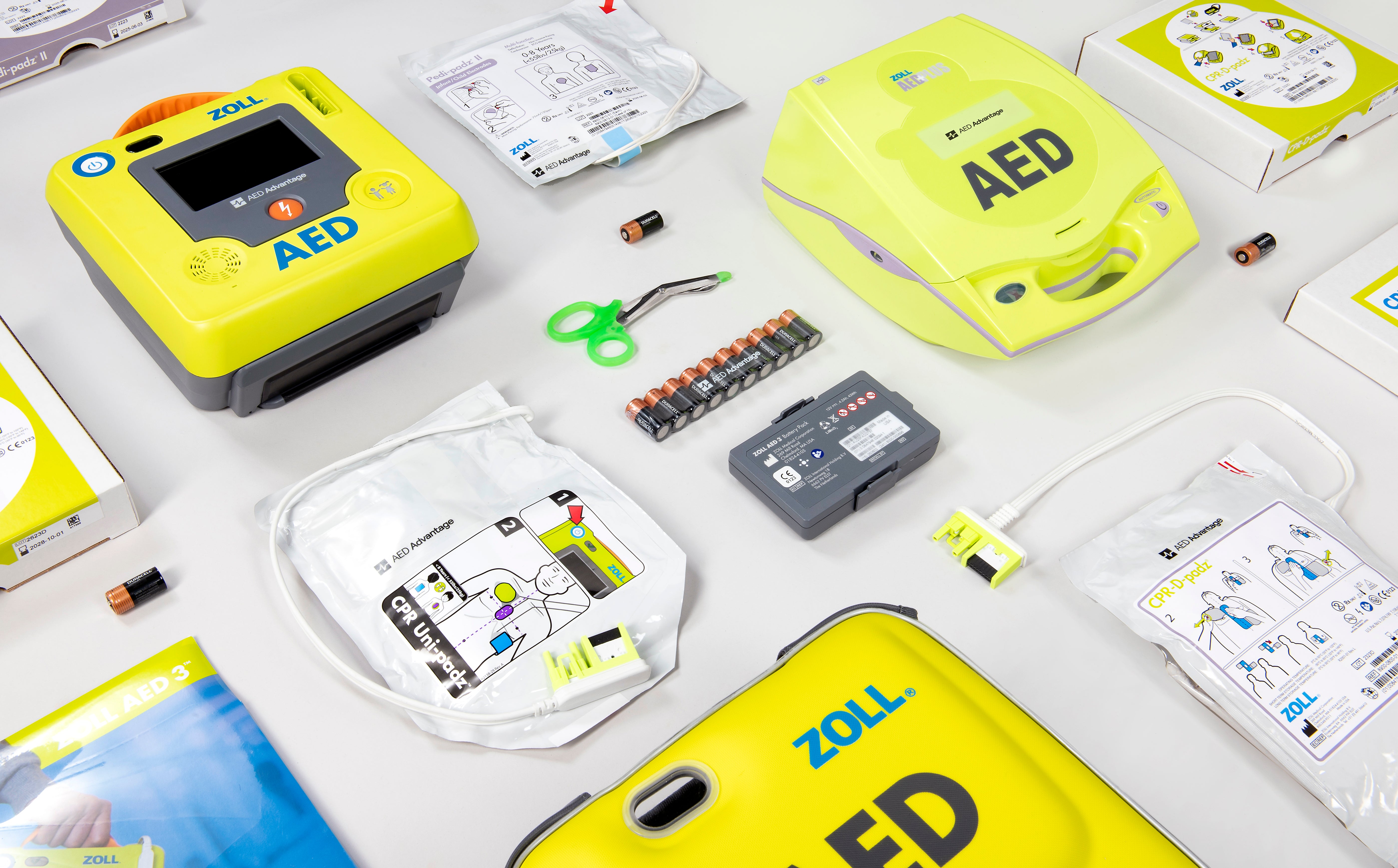 A collage green AEDs and their replacement batteries and electrode pads