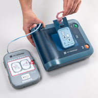 Someone is inserting a pediatric key into a blue Philips HeartStart FRx AED