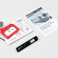 White foil package containing adult AED pads, a small black battery, and an instruction booklet 