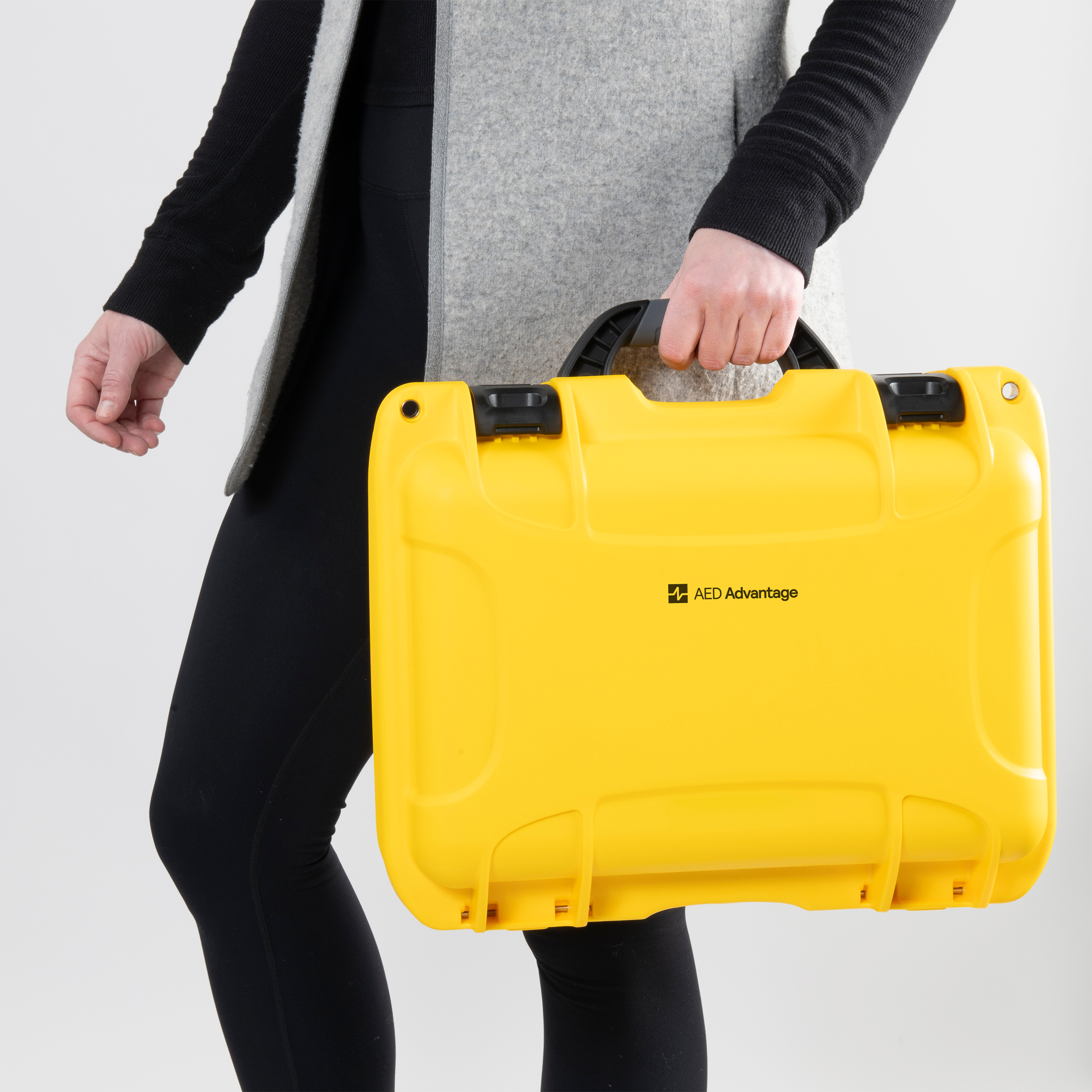 A woman holding a bright yellow hard shell aed case.