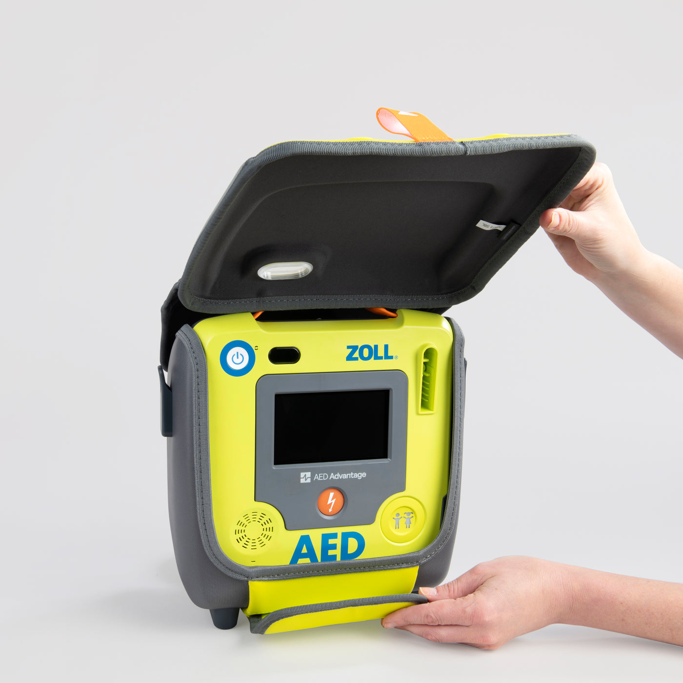 A bright green ZOLL defibrillator's carry case is being opened by hand to display the AED
