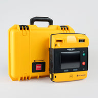 A bright yellow hardshell AED case with a black and yellow LIFEPAK 1000 AED standing in front.