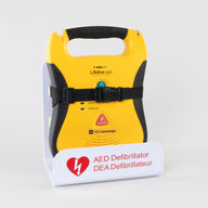 A black and yellow Defibtech Lifeline AED strapped into a white metal wall mount bracket