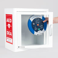 A blue and white HeartSine 500P AED being retrieved by hand from a white metal cabinet with red decals