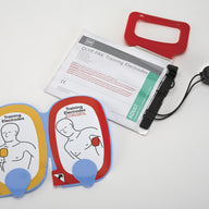 A white foil pouch and its contents which are colorful training electrodes for the CR Plus AED
